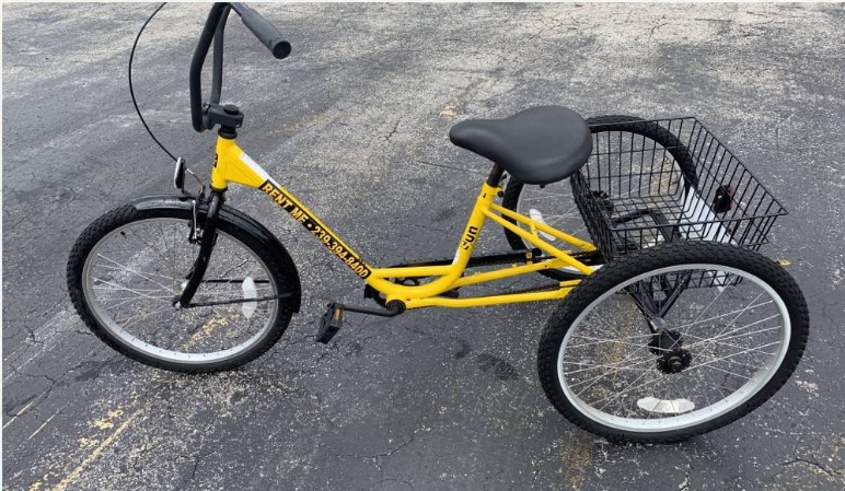 A yellow trike parked on a sunny Marco Island street near Tigertail Beach, showcasing its three-wheeled stability.