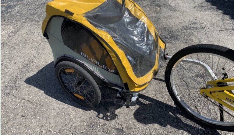 A child pull behind trailer towed by an adult bike near Tigertail Beach on Marco Island, featuring a canopy and padded seats.